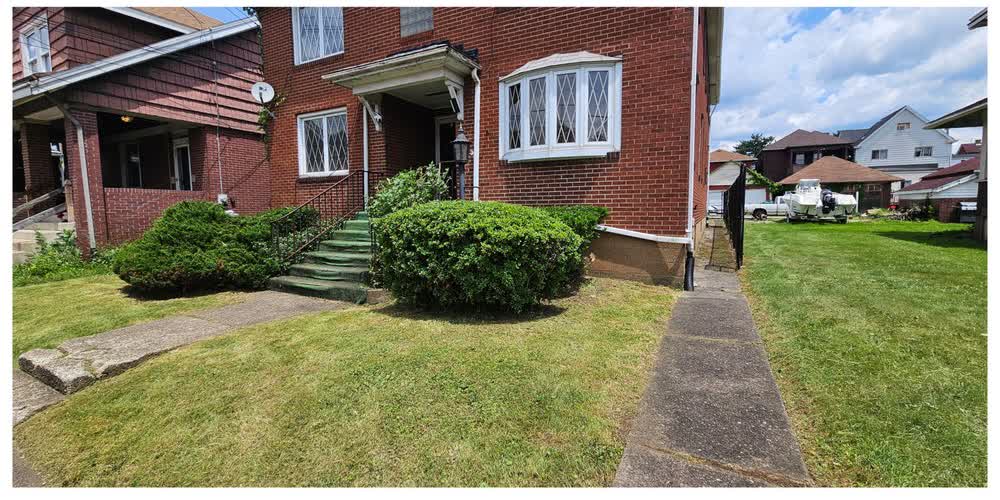 The same foundation bed after cleanup, with a neatly trimmed rounded hedge and clear walkway