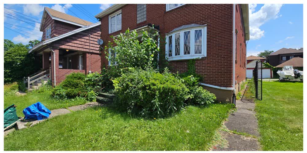 A severely overgrown shrub and foundation bed before cleanup